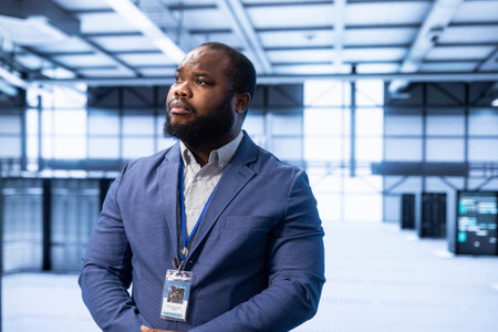 Engineer walking in data center, configuring and managing network infrastructure, such as routers, switches and firewalls. IT expert in server hub looking for technical issuesの写真素材