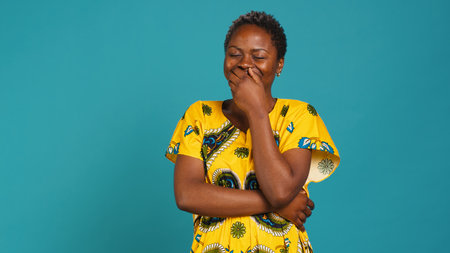 Feminine natural young girl laughing at something in studio, wearing a traditional attire with native floral elements. Confident woman representing the ethnic tradition with clothing. Camera A.の写真素材