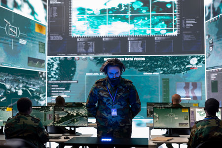 Army officer analyzing surveillance data on a hologram projection, reviewing registered information from satellite surveillance system. Looking at new defense operation details in power base.の写真素材