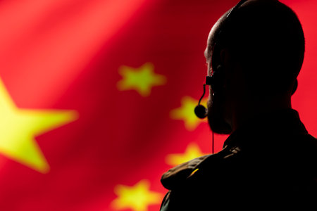 Chinese military dispatcher using headset mic, offering information to commanders fighting on front lines during war. Counterintelligence agent providing direction for troops, isolated over China flagの写真素材