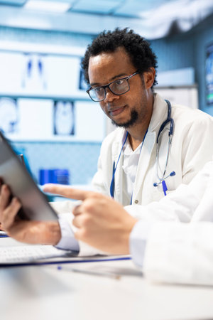 Diverse team of medics examining x ray results and healthcare data in a cabinet meeting, consulting the colleagues before putting a diagnostic. Physicians working together for healthcare recovery.の写真素材
