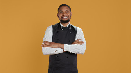Portrait of restaurant waiter wearing professional uniform and apron getting ready to assist and...