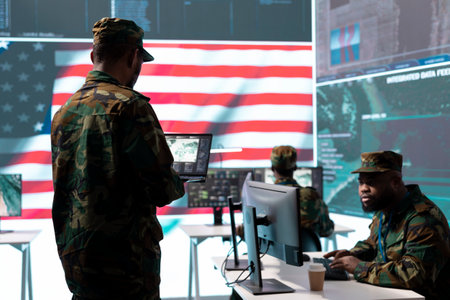 US soldiers in a high tech command center protecting classified information, ensuring cybersecurity and defending against cyber attacks. Army base of operations with trained officers.の写真素材