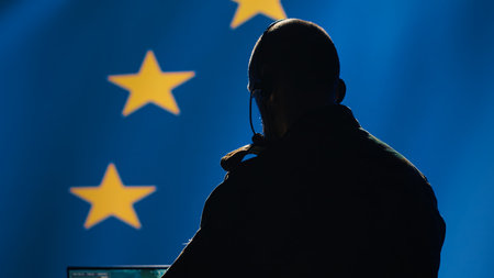 European Union military dispatcher looking at surveillance broadcast, relaying informations for troops using headset. Telecommunications operator over EU flag background, coordinating troops, camera Aの写真素材