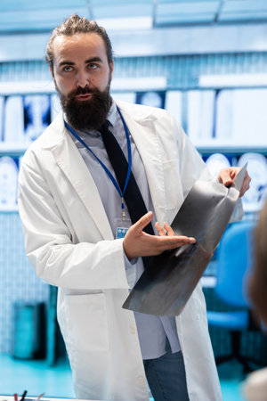 General practitioner gathering healthcare experts review x ray scans in a private clinic meeting. Licensed professionals focusing on diagnostics and disease prevention, collaborative teamwork.の写真素材