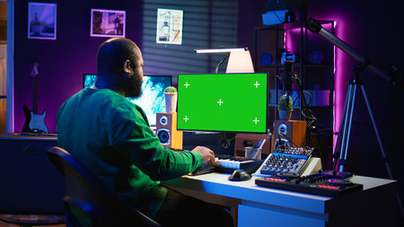 Songwriter operates on synthesizer piano keys next to isolated display, composing new music with instruments and stereo tools in home studio. Artist producer works with green screen. Camera B.の写真素材