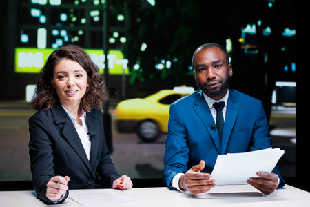 Diverse newscasters reading headlines in news studio, working in television industry to create exclusive content. Team of live journalists covering all important topics, entertainment segment.の写真素材