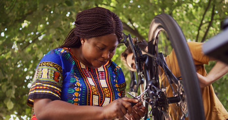 Young and sporty couple mending bicycle damages with specialized multitool in home yard. Healthy caucasian man and black woman selecting suitable allen key head for bike adjustments.の写真素材