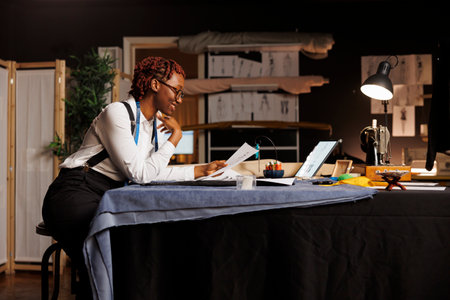 Experienced seamstress apprentice amuzed by quirky handdrawn sketches made by master fashion designer for upcoming runway show. Cheerful skilled tailor working on custom made sartorial collectionの写真素材