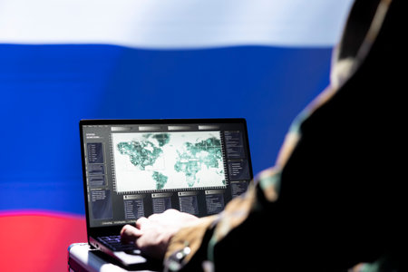 Russian army specialist working for Kremlin regime using target acquisition tech on laptop to detect enemy location. Ex KGB military officer isolated over Russia flag using satellite deviceの写真素材
