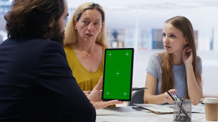 Broker holding green screen tablet, meeting with clients to provide stock exchange analysis. Financial advisor with chroma key device looking at market shares, helping family maximize income, camera Bの写真素材