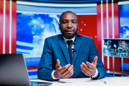 News anchor presenting daily events on global television program, covering all latest topics regarding public life and celebrities. African american reporter transmitting live information.の写真素材