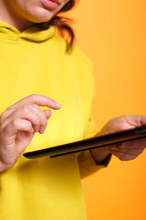 Close-up of female hand holding digital tablet with technology and working on internet. Caucasian woman holding device with touch screen, working on website with display of a gadget.の写真素材