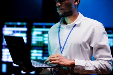 Manager using laptop to survey high tech supercomputers providing vast computing resources and storage. Server farm enabling artificial intelligence to process massive datasets for trainingの写真素材