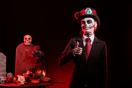 Portrait of jolly woman doing thumbs up gesture during Day of the Dead event honoring dead loved ones. Satisfied lady doing approval gesturing during ancient Aztec custom of celebrating ancestorsの写真素材