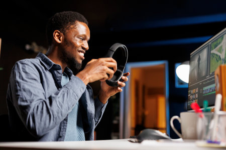 Editing specialist enhancing gradient on film montage, working from home with color correction toolbar and gradient. African american video maker edits clips footage for new movie scene.の写真素材