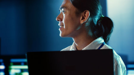 Close up shot of happy employee wandering around data center infrastructure providing processing resources for different workloads. Smiling admin doing analysis on serversの写真素材