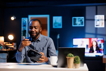 Tech influencer filming sponsored branded content, unboxing newly released VR glasses product. Cheerful entertainer presenting virtual reality headset parameters to subscribersの写真素材