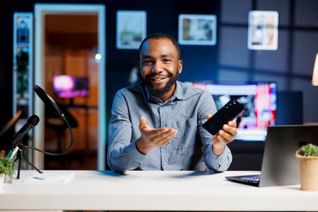 Internet show host promoting smartphone received from sponsoring brand to fans. BIPOC media star does influencer marketing on online channel, urging followers to purchase mobile phoneの写真素材