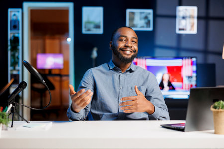 Cheerful BIPOC content creator doing travelling recommendations type of video for fans, giving tips, filming in his apartment. Online show host sharing with viewers his favorite locations in the worldの写真素材
