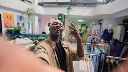 Man filming POV vlog while doing shopping in elegant fashion boutique, giving viewers info. Influencer doing social media content in clothing store, promoting clothing store new collection stockの写真素材