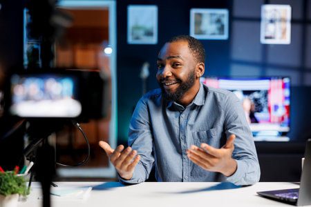 African American content creator using high quality recording gear to shoot intro for vlog channel on online streaming platforms. Media star warmly welcoming dedicated fanbase, introducing video topicの写真素材