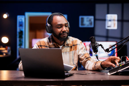 African american content creator adjusting knobs on sound mixer for good audio quality while recording a vlog. Black male blogger using professional equipment for filming channel intro for viewers.の写真素材