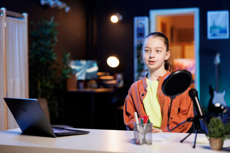 Child filming room tour inside blue neon illuminated home studio. Gen Z influencer using professional equipment to record video presenting apartment to interested children audienceの写真素材