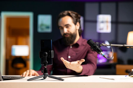 Close up shot of cellphone assessed by tech expert in studio talking about parts used inside. Focus on phone reviewed by entertainer in blurry background for technology internet channelの写真素材