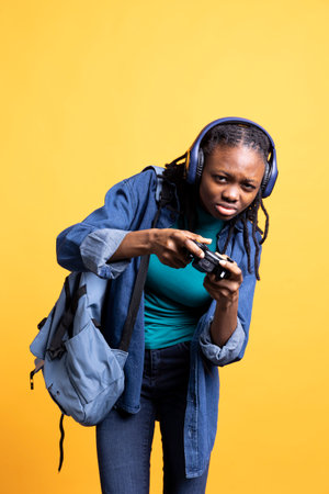 African american gamer holding controller, squinting eyes, trying to finish videogame level, wearing headphones. Woman gaming with gamepad, defeating other players, studio backdropの写真素材