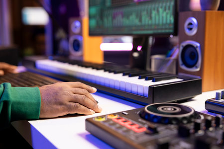 Sound designer operates on mixing console and digital software to edit audio files, adjusting volume levels with pre amp knobs in home studio. Technician produces new music on stereo gear. Close up.の写真素材