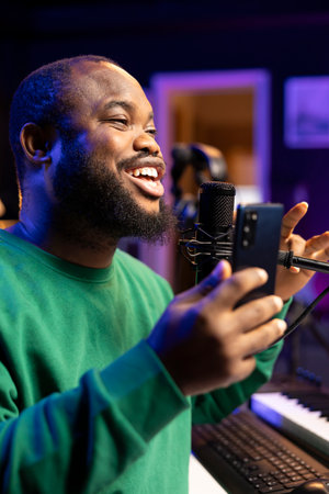 Composer songwriter performing acoustics for his new song in home studio, editing the tunes with mixing console. Artist musician recording tracks on microphone, creative melodic elements. Close up.の写真素材