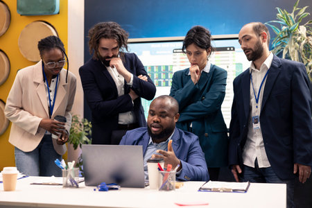 Diverse business colleagues reviewing project details to ensure objectives accomplishment, calculating infographics on laptop and finding ways to increase financial activity. Business management.の写真素材