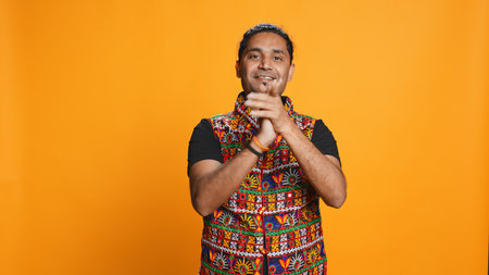 Joyful indian man happily clapping hands, ecstatic about accomplishments. Excited person reacting to good news, cheering, applauding, isolated over studio background, camera Bの写真素材