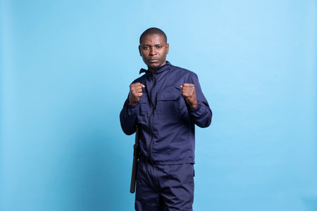 Professional security agent poses with clenched fists in studio, on protection duty ready for a fight in order to safeguard something. Armed guard with proper combat and defense training.の写真素材