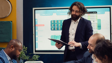 Team leader sharing clipboards with the latest performance metrics to discuss about work efficiency and optimization during corporate briefing meeting. Manager is consulting his personnel. Camera A.の写真素材