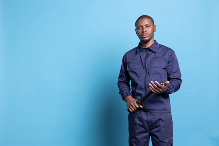 Security officer holding his baton in his hands while on guarding duty, working on protecting the perimeter. Professional trained agent with patrolling uniform poses against blue background.の写真素材