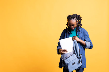 Woman opening backpack to take encyclopedia books out for school project, isolated over studio background. Student removing textbooks from schoolbag, using them for academic purposesの写真素材