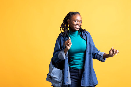 Thrilled african american young girl doing happy dance, feeling joyful, isolated over studio background. Portrait of euphoric woman celebrating achievement, doing positive hand gesturesの写真素材