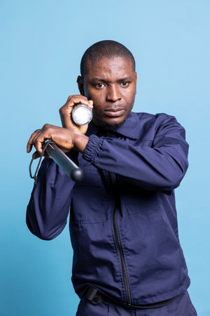 Serious security agent doing a control sweep in the dark with his flashlight, keeping his weapon close for protection. Mall armed guard using lantern and patrolling the premises.の写真素材
