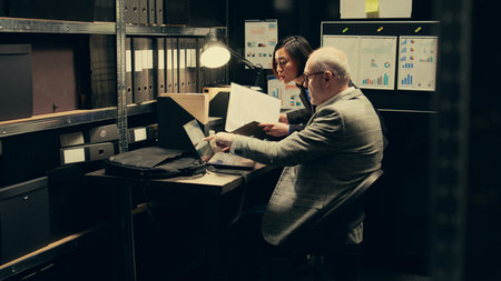 Detective team examines archived files for crucial case evidence, working in incident room with classified documents. Inspectors remain relentless in the pursuit of justice, police archive. Camera B.の写真素材