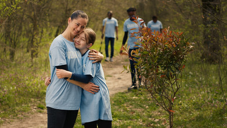 Portrait of mom and child protecting the environment by collecting rubbish, activism. People cultivating consciousness by eliminating plastic pollution and trash from the woods. Camera A.の写真素材