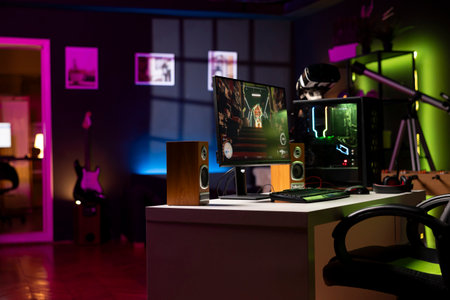 Empty apartment living room with neon lights and gaming computer with first person shooter game left open on monitor. Singleplayer videogame on desktop pc display on desk late at nightの写真素材