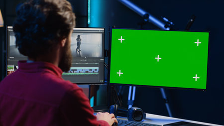 Video editor selects key frames to use in movie montage, using specialized software applications on green screen computer monitor. Freelancer using editing tools on chroma key PC, cutting footageの写真素材