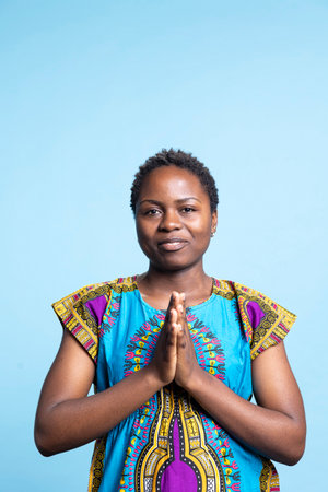 Wearing customary ethnic attire, african american woman worshipping and communicating with Christ in...