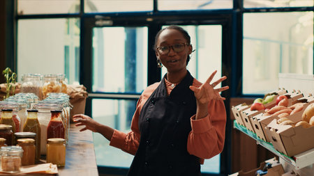 Merchant talking about her nonpolluting small business, presenting locally grown ethically sourced produce on social media ad. Saleswoman filming video to promote her eco friendly food. Tripod shot.の写真素材
