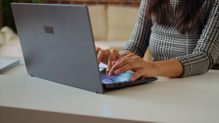 Teleworker writing emails on laptop, sending them to business partners. Employee working from home in bright stylish cozy apartment personal office, typing on notebook keyboard, camera A close upの写真素材
