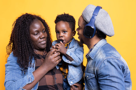 Proud mother and father listening to their toddler sing a song in studio, african american dad...