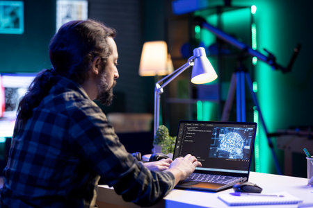 Youthful man using machine learning to manage a complex system on his laptop. Male individual...