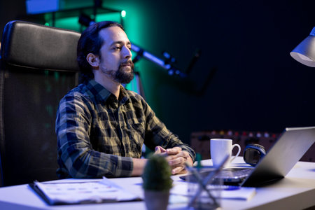 An image of a man sitting at a desk, staring at the camera with his hands crossed. Dedicated man...